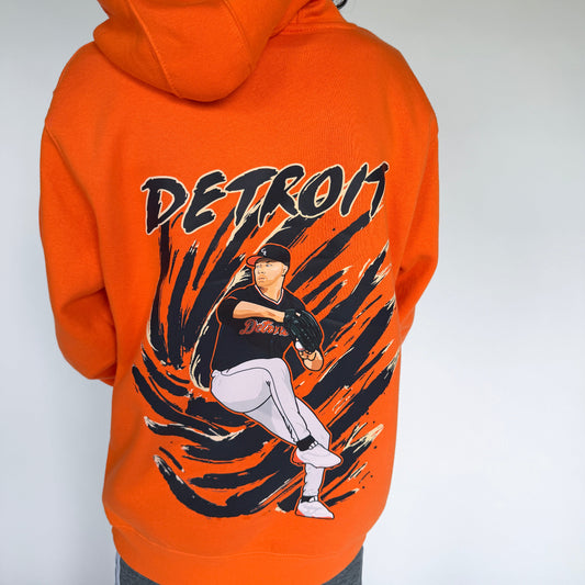 Person wearing an orange hoodie with 'Detroit' and a baseball player graphic on the back.