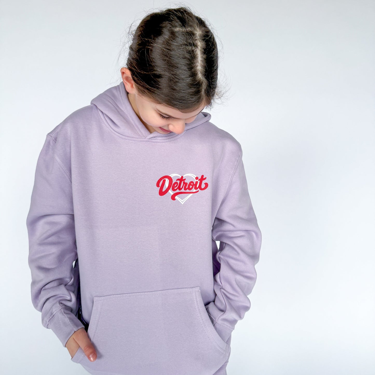 Person wearing a light purple hoodie with 'Detroit' printed on it against a white background